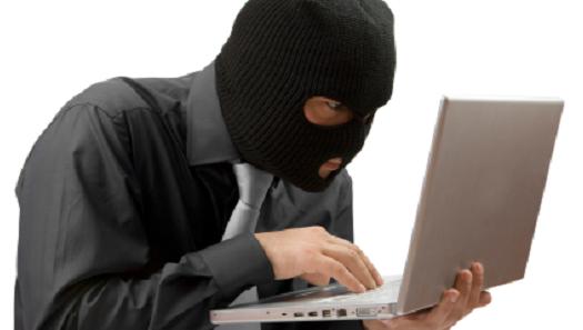 person wearing a ski mask and holding a laptop